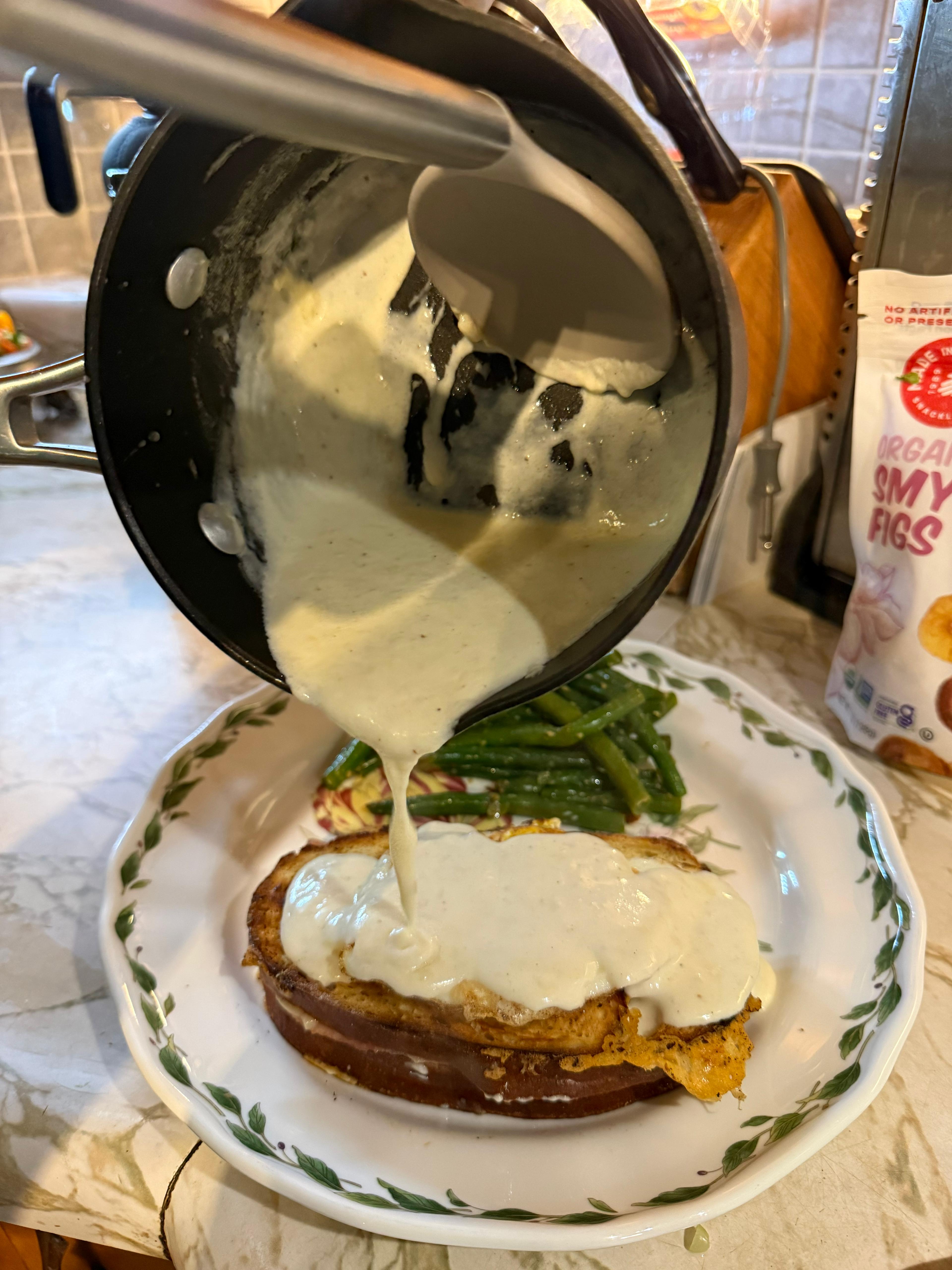 Pouring béchamel over the croque madame